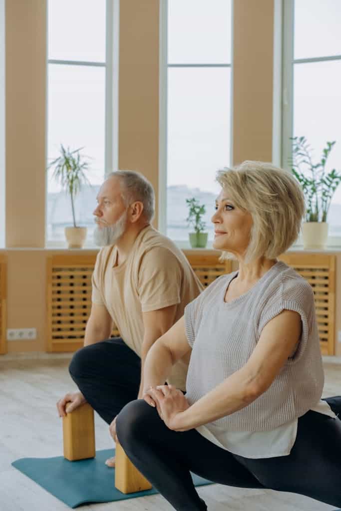 A senior couple practicing yoga indoors, focusing on flexibility and wellbeing.