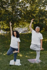 A mature couple enjoying yoga exercises together in a sunny park setting.