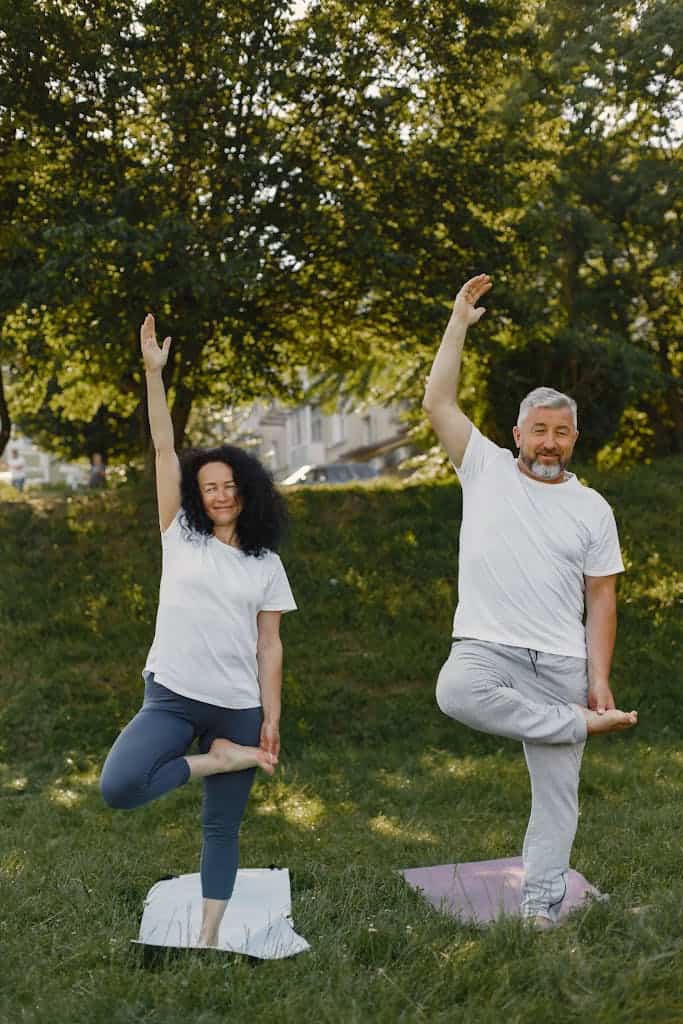 A mature couple enjoying yoga exercises together in a sunny park setting.