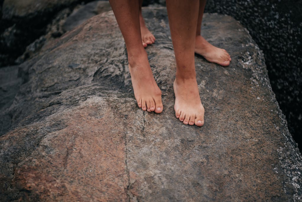 Close-up of bare feet standing on a large rock surface outdoors, capturing a natural and earthy vibe.